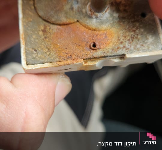 חלק מתכתי חלוד מוחזק בידיים